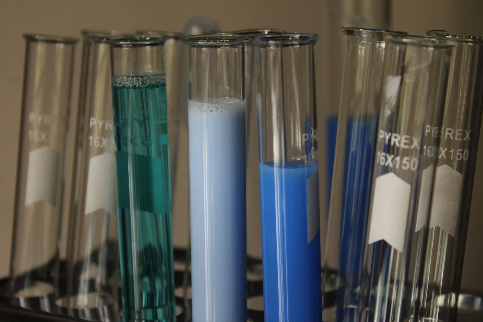Close-up of colorful chemical solutions in glass test tubes in a laboratory setting. How OSHA and EPA rules shape chemical storage on a US pool route