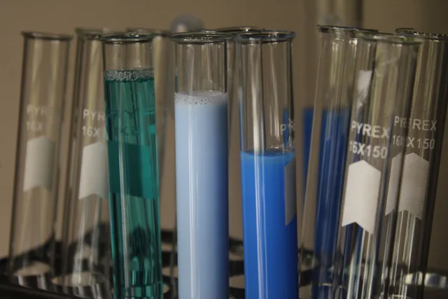Close-up of colorful chemical solutions in glass test tubes in a laboratory setting. How OSHA and EPA rules shape chemical storage on a US pool route
